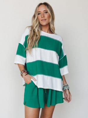 A relaxed matching set in bold kelly green and white stripes — the oversized tee and pull-on shorts feel effortlessly cool, styled with stacks of beaded bracelets that give it just the right amount of personality.