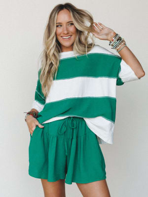 A bright, easy two-piece set in kelly green and ivory stripe — the kind of outfit that looks pulled-together without trying, styled with stacks of beaded bracelets and a genuine smile.