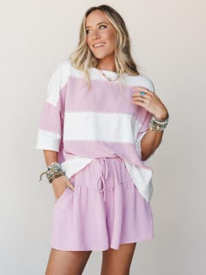 A relaxed two-piece matching set in orchid pink and ivory wide stripes — the oversized tee and drawstring shorts feel like the kind of outfit you wear when you want to look put-together without trying too hard, styled with stacks of boho bracelets th