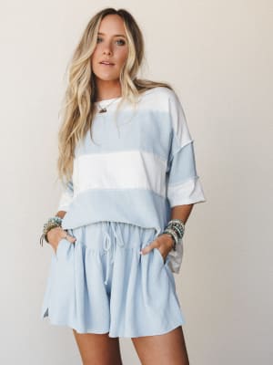 A relaxed two-piece matching set in soft sky blue and ivory colorblock, styled with stacked boho bracelets and a delicate necklace — the kind of effortless outfit that looks like you tried just enough.