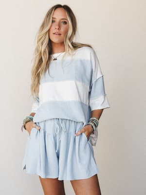 A relaxed two-piece matching set in soft sky blue and ivory colorblock, styled with stacked boho bracelets and a delicate necklace — the kind of effortless outfit that looks like you tried just enough.