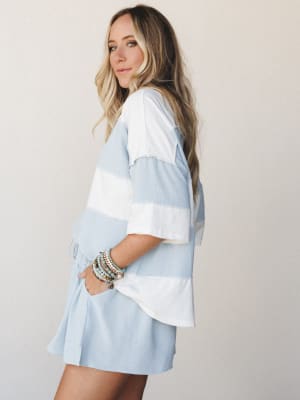 A relaxed two-piece matching set in wide-stripe sky blue and ivory, styled with stacked beaded bracelets — the kind of effortless warm-weather outfit that looks just as good on a patio as it does at the farmers market.