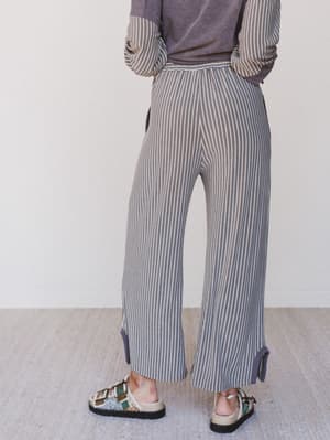 Person wearing a striped outfit with wide-leg pants on a neutral background