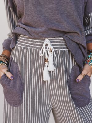 Person wearing a purple top and striped pants with tassel details.