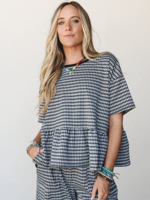 A gingham matching set styled with stacked beaded bracelets and a colorful beaded necklace — casual and collected, like she threw it on and somehow made it look intentional.