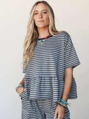 A gingham matching set styled with stacked beaded bracelets and a colorful beaded necklace — casual and collected, like she threw it on and somehow made it look intentional.