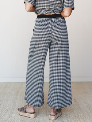 A wide-leg gingham pant styled as a matching set, shot from the waist down against a soft neutral interior — relaxed and put-together at the same time, with leopard print espadrille platforms adding just the right amount of personality.