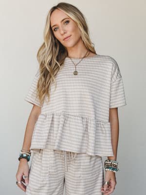A matching gingham set in warm sand and white — the peplum top and drawstring pants feel like the kind of outfit you'd reach for every Saturday without thinking twice, styled with layered gold necklaces and stacked beaded bracelets for that effortles