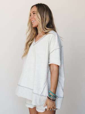 A relaxed short set in light heathered grey worn with a stack of boho bracelets — effortless and lived-in, the kind of outfit that somehow looks intentional even at 8am.