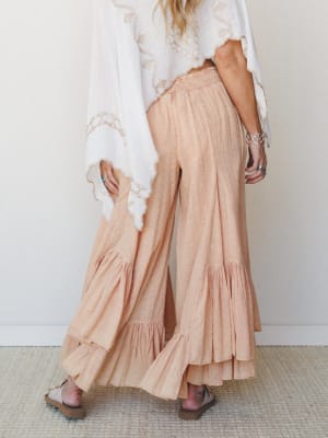 Dreamy wide-leg ruffle pants in a soft peach-coral gauze paired with a flowing embroidered white top — the kind of outfit that makes even a Tuesday feel intentional.