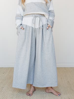 A relaxed, heathered gray wide-leg pant with a drawstring waist is styled with a matching colorblock sweatshirt — the kind of set that makes staying in feel intentional.
