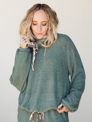 A cozy boucle lounge set in deep sage green, styled with stacked silver and turquoise rings — the kind of outfit that makes staying in feel like a whole personality.