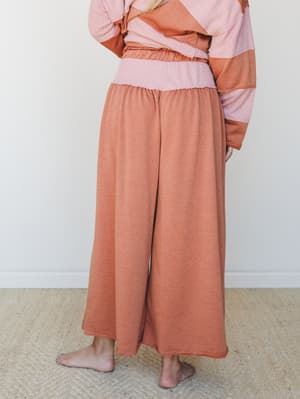 A back-view shot of wide-leg pants in a warm camel tone, styled with a coordinating color-block ribbed sweatshirt — the whole set feels like the kind of cozy you actually want to be seen in.