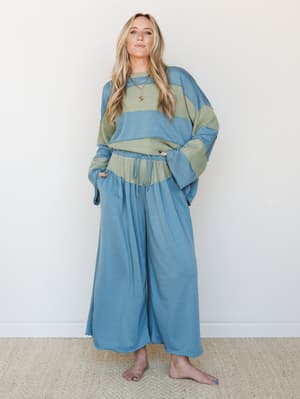 A relaxed two-piece matching set in dusty teal and sage, styled with easy wide-leg pants and an oversized color-block sweatshirt — the kind of outfit that looks intentional without trying.