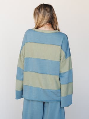 Shot from the back, this relaxed mixed-fabric top pairs dusty teal sweatshirt panels with sage green waffle-knit stripes — worn as a set with matching wide-leg pants, it has that effortless 'I put this together in two seconds' energy.