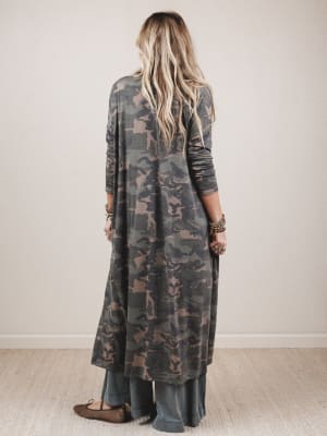 Person wearing a long camouflage dress against a plain background