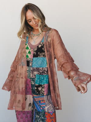 A rose brown sheer lace kimono layered over a vibrant mixed patchwork jumpsuit — the kind of outfit that looks like it was put together effortlessly but definitely wasn't.
