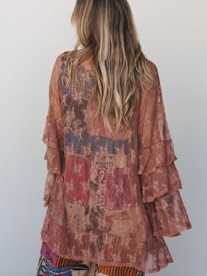 Shot from behind, a sheer rose brown kimono layered over a mixed-print skirt — the ruffled bell sleeves and floral lace overlay do most of the talking, in the best way.