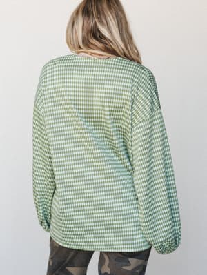 Shot from the back, this relaxed gingham cardigan in avocado green pairs effortlessly with camo pants — a casual, lived-in combo that feels totally intentional.