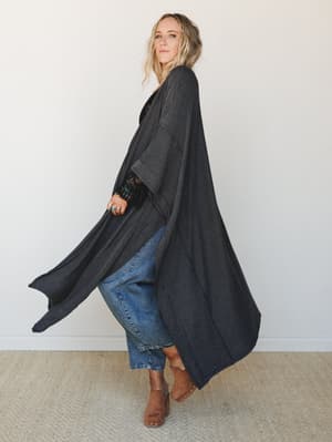 A flowy, floor-length duster kimono in charcoal stripe layers over cropped denim and tan studded mules — the kind of outfit that looks effortless but clearly had a thought behind it.