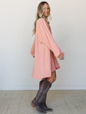 A breezy striped mini dress in warm peach and sage paired with dark brown cowboy boots and turquoise rings — the kind of outfit that looks just as good at a weekend market as it does at a backyard concert.