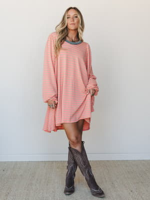 A flowy striped mini dress in coral and slate paired with tall dark brown cowboy boots — the kind of outfit that looks effortless but definitely wasn't an accident.