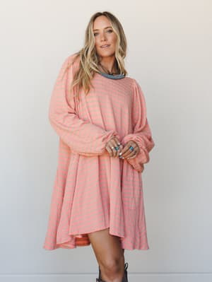 A relaxed striped mini dress in peach and sage worn with cowboy boots and layered turquoise jewelry — the kind of outfit that looks effortless but definitely wasn't an accident.