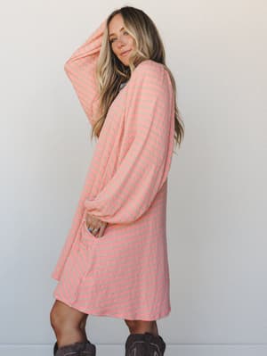 A relaxed midi dress in a soft coral-and-sage stripe worn with dark cowboy boots — the kind of effortless outfit that looks like you tried just enough.