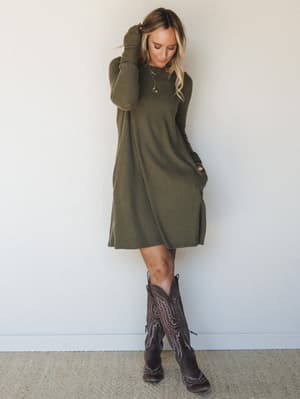 A ribbed olive mini dress with a relaxed swing silhouette gets grounded by dark brown cowboy boots — the kind of effortless fall outfit that looks like it came together in five minutes but definitely didn't.