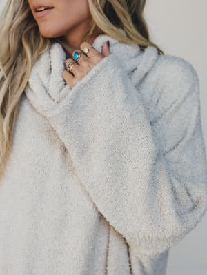 Person wearing a soft, light-colored sweater dress with a neutral background