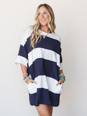An oversized navy and white stripe mini dress in a textured gauze fabric, styled with stacked turquoise bracelets and a charm necklace — effortless and a little coastal, like something you'd throw on after the beach and somehow still look completely