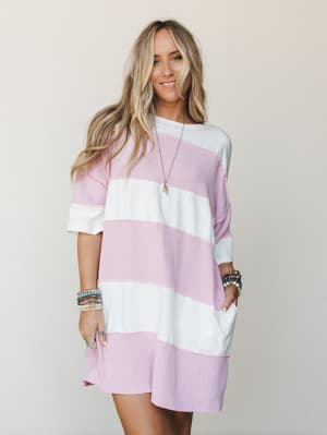 A relaxed mini dress in wide orchid pink and ivory stripes worn with stacked beaded bracelets and a long pendant necklace — the kind of effortless summer outfit that looks like you tried just enough.