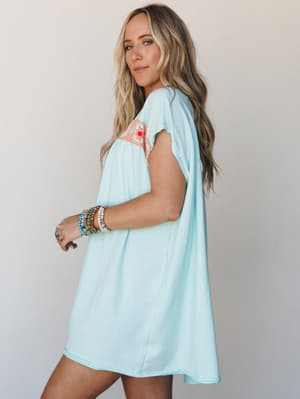 A breezy light mint mini dress with a crochet chest panel in warm coral and pink tones, styled with stacked boho bracelets and a turquoise ring — easy and expressive in the best possible way.