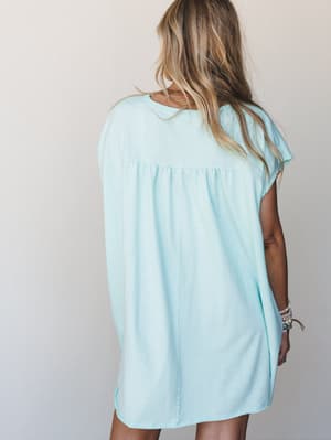 Shot from the back, a breezy mint t-shirt dress with a gathered yoke detail hangs relaxed and easy on the model — the kind of dress you throw on and somehow look completely put-together.