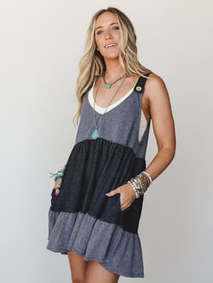 A tiered colorblock babydoll mini dress styled with stacked boho bracelets and layered turquoise necklaces — the kind of effortless outfit that looks like you tried just enough.