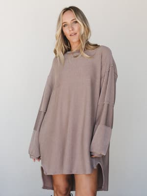 An oversized ribbed knit mini dress in a warm taupe-brown worn relaxed and easy — the kind of thing you reach for when you want to feel put-together without trying too hard.