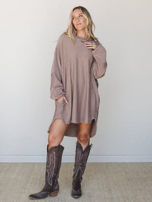 An oversized ribbed mini dress in warm acorn brown styled with tall dark brown cowboy boots — the kind of effortless, lived-in look that walks out the door fast and still turns heads.