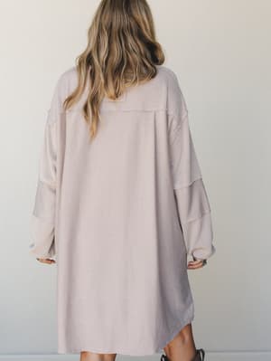 Shot from the back, this oversized waffle-knit mini dress in a soft oat and lavender two-tone texture has that effortless 'grabbed it off the chair' energy — wide balloon sleeves, relaxed A-line silhouette, and exposed seam details that feel intentio