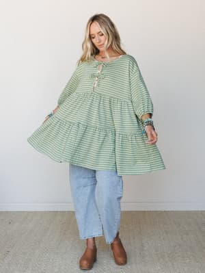 A flowy, oversized gingham top styled with wide-leg light wash jeans and tan clogs — the kind of effortlessly lived-in outfit that makes a Tuesday feel intentional.