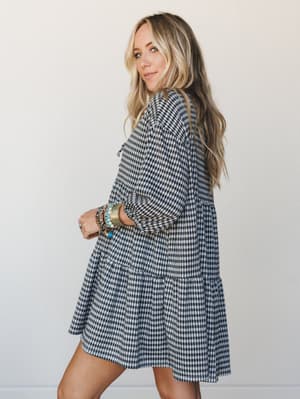 A breezy gingham mini dress styled with a stack of boho bracelets — the kind of effortless, lived-in look that works just as hard at brunch as it does at a fall farmers market.