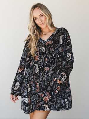 A relaxed velvet mini dress in a bold black paisley print worn with effortless ease — the kind of piece that looks like you tried just enough.
