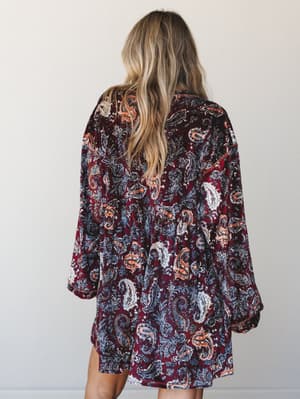 Shot from the back, this velvet mini dress in a rich burgundy paisley print has a relaxed, flowy silhouette with billowy long sleeves — the kind of dress that feels as good as it looks on a crisp fall evening.