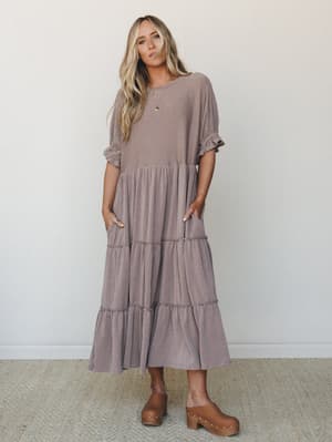 A tiered ribbed maxi dress in a warm muted mauve-taupe worn with wood platform clogs — the kind of effortless, lived-in look that feels equally at home on a coffee run or a weekend away.