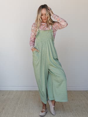A wide-leg gingham jumpsuit in sage green layered over a sheer floral long-sleeve top — the kind of mix-and-match energy that looks effortless but was definitely thought about.