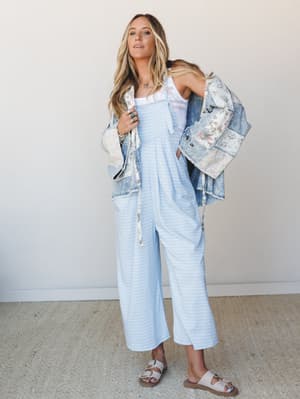 A breezy, effortless look built around a wide-leg gingham jumpsuit layered under a floral-patched denim jacket — the kind of outfit that feels like a good mood and works just as hard at the farmer's market as it does at a rooftop lunch.