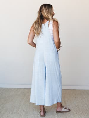 Shot from behind, a wide-leg gingham jumpsuit in soft sky blue reads effortlessly warm-weather-ready — the kind of thing you throw on and somehow look totally put-together.