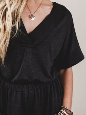 Person wearing a black dress with a plain background