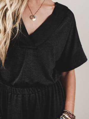 Person wearing a black dress with a plain background