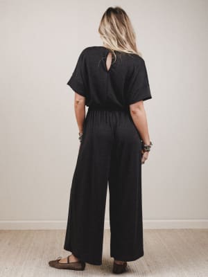 Person wearing a black jumpsuit with a plain background