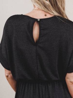 Black dress with open back worn by a person on a neutral background